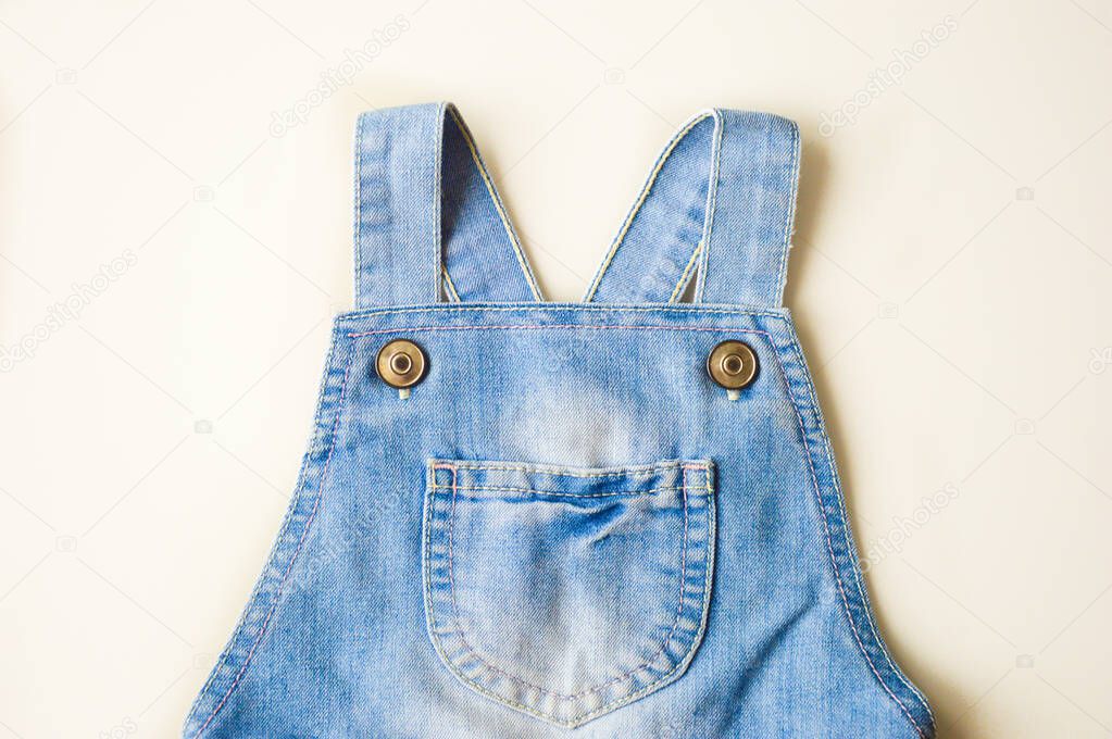 Straps from a denim jumpsuit on a white background.
