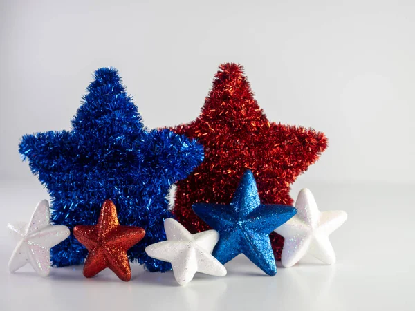 Blue and Red tinsel stars with blue, white and red glitter stars in front on a white background for Memorial Day, 4th of July, Independence Day, Veterans Day or patriotic love the USA.