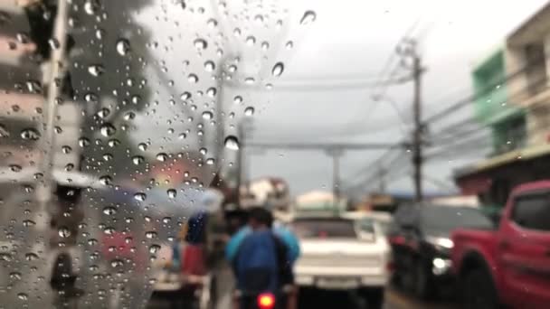 車のフロントガラスに雨滴の専用画像 市内の道路上のぼやけたトラフィック 暴風雨で車を運転 街路灯のカラフルなボケ 選択的フォーカス — ストック動画