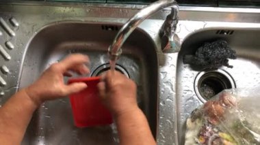 Yaşlı Asyalı bir kadının eli bulaşık, kase ve bardakta su ve sabunla kırsal mutfakta, üst tarafta..