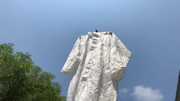 Protective PPE suit hanging outdoor after the used and washing,natural glare light,the ppe suit can to repeated use 2-3 times,after use every day should wash and dry in the sun,prevented covid-19.