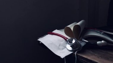 Engellenen covid-19 konsepti, sağlık bakımı. Stetoskop, tıbbi kardiyolog, hijyenik maske, bulanık kitap sayfaları, kalbi eski ahşap üzerinde şekillendirmek gibi, loş ışık. Kırsal yaşam ve karanlık arka plan..