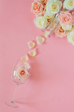Sevgililer Günü 'nde pembe arka planda şarap kadehinde pembe güller vardı. Düz görünüm arkaplan kavramı
