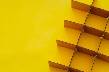 Arkaplan ve desenli kavram için sarı zemin üzerinde kare şeklinde kesilmiş ve ayarlanmış karton kutu.