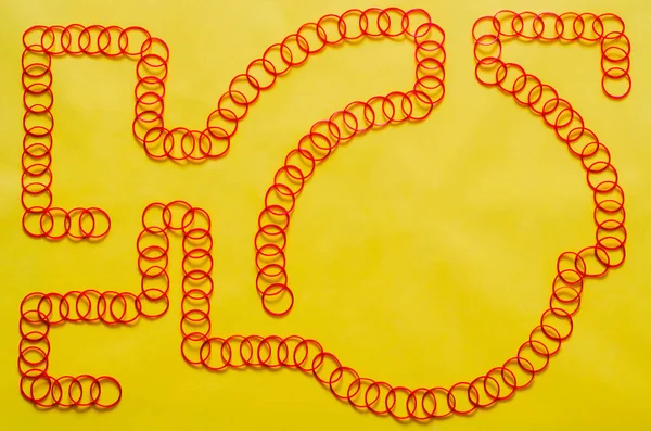 Red color elastic rubber bands arrange in line shape put on yellow background with empty space for background and abstract concept
