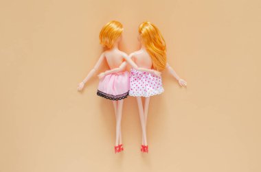 Üstte çıplak iki kadın bebek, bej arka planda birbirlerine sarılıyorlar. Gurur günü ve sıfır ayrımcılık kavramı.