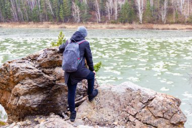 Bir turist uçurumdan nehre bakar, buzun üzerinde yüzer.