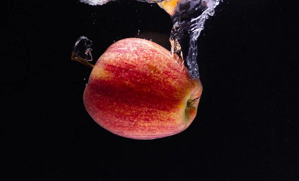 Kırmızı bir elma suya düşer ve siyah bir zeminde güzel bir su girdabı yaratır.