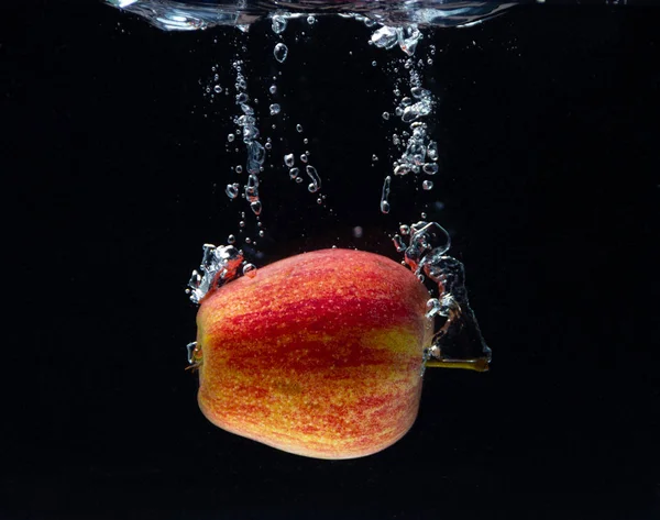 Kırmızı bir elma suya düşer ve siyah bir zeminde güzel bir su girdabı yaratır.