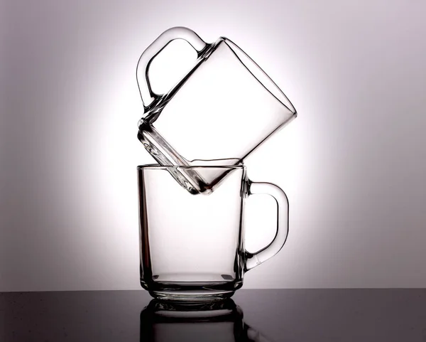 Szklaną przezroczystą filiżankę herbaty stoi na innym kubku na ciemnym tle — Zdjęcie stockowe
