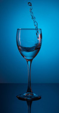 Güzel, mavi bir arkaplanda bardakta bir damla su.