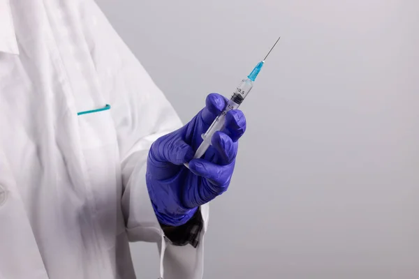 Elinde ilaç ve şırınga şişesi olan bir tıp çalışanı.