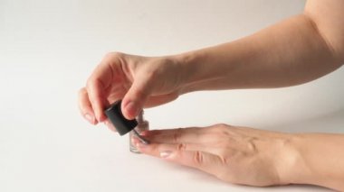 Eller beyaz arka planda ojeyle oje sürerler. Pullu Polonyalı. Bir fırçayla dikkatlice oje sürdüm. Güzellik salonlarının, kuaförlerin, manikürcülerin, manikürcülerin, manikürcülerin uzmanları.