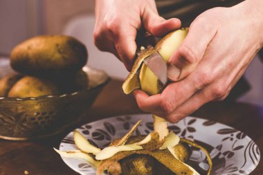 Evde bıçakla patates soyuyordu.