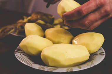 Evde bıçakla patates soyuyordu.