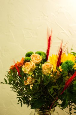 Gri arkaplandaki vazoda farklı renklerde güzel buketler.