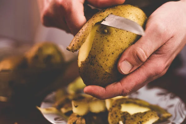 Evde bıçakla patates soyuyordu.