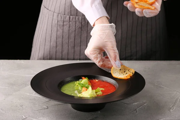 tomatoes soup with hands. chef decorating plate.