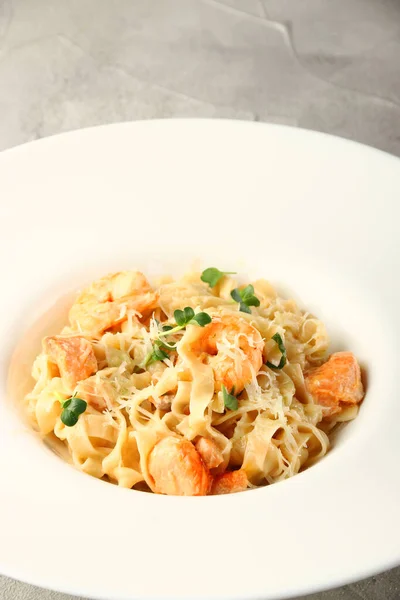 Kapalı deniz mahsullü makarna. Beyaz tabakta karides ve somonlu makarna.