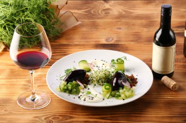 Salatalık salatası, ezmeli ve ahşap arka planda mikroyeşil tabakta. salata ve kırmızı şarap