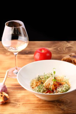 Ahşap masa ve beyaz şarapla süslenmiş kalamar ve peynirli domates çorbası.