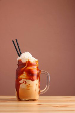 Tahta masada kahve ve karamelli milkshake. Tuzlu karamelli dondurma. Soğuk kahve frappe frappuccino, kremalı.
