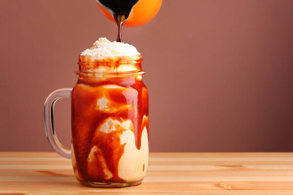 pouring coffee in milkshake frappuccino . Cold coffee drink frappe frappuccino , with whipped cream and caramel syrup. Salted caramel