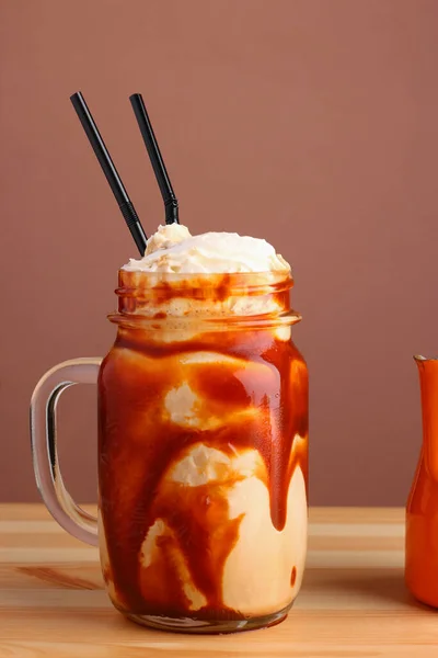 caramel milkshake with coffee on wooden table. Salted caramel ice cream sundae. Cold coffee drink frappe frappuccino , with whipped cream