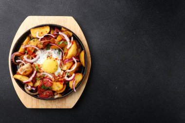 Patatesli tava et ve siyah betonun üzerinde yumurta. Meksika yemeği konsepti. Tavada kızarmış patates.