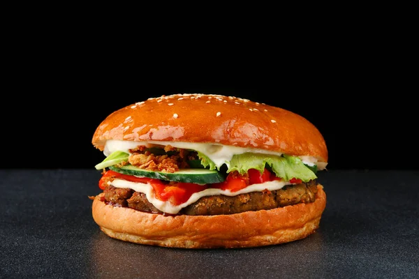 tasty burger with chicken on dark isolated back. Homemade hamburger or burger with fresh vegetables and cheese