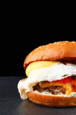 Koyu izole edilmiş arka planda yumurtalı burger. Taze sebze ve peynirli ev yapımı hamburger veya hamburger.