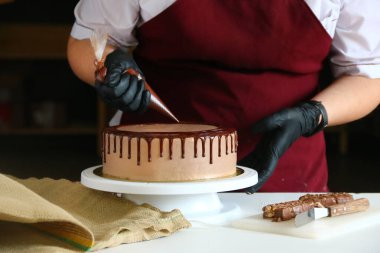 Pastanın üstüne çikolata. Şekerci, hamur torbasından kremalı bisküviye kadar sıvı çikolata sıkıyor.