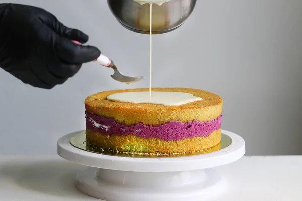 confectioner decorate blueberry cake. cake making process. dessert with confectioner hand on light back