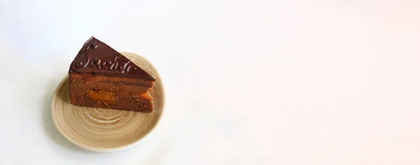 Chocolate Austrian cake sacher sliced on white table back. Sacher cake slice. Traditional Austrian chocolate dessert. Homemade baking. Selective focus, close-up.