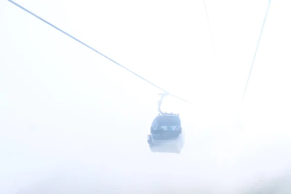 Cable car in the fog with beautiful high mountains in the background — Stock Photo, Image