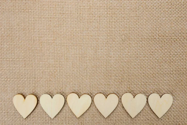 Corazones de madera sobre fondo de textura hessiana, fondo de San Valentín — Foto de Stock