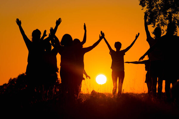 Silhouette of several people practicing yoga in the field