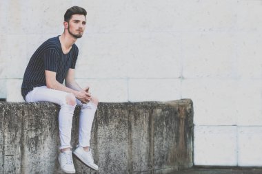 duvarda oturan ve düşünme genç adam. Pensative adam