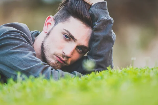 Retrato de cerca de un joven acostado en un jardín verde. Hombre. — Foto de Stock