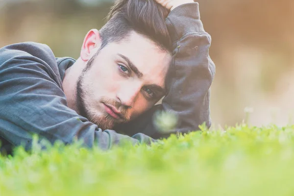 Närbild porträtt av en ung man liggande en grönskande trädgård. Mannen — Stockfoto