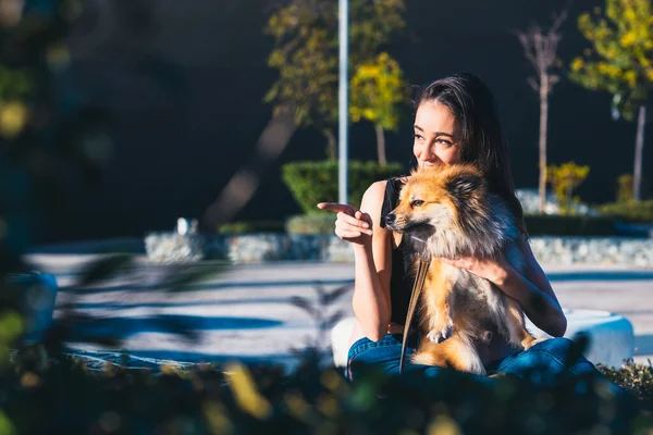 Genç bir kadın köpeğini elleriyle gösteriyor. Metin için alanı kopyala