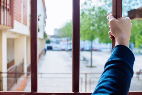 a woman's hand grabbing the bars of a window.