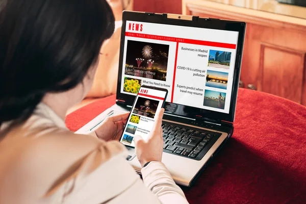 Tablet ve dizüstü bilgisayardan haberleri okuyan kadın.