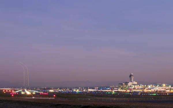 美国俄勒冈州波特兰- 2019年10月：波特兰国际机场的长期曝光照片和飞机从机场起飞后天空中的光迹. 免版税图库图片