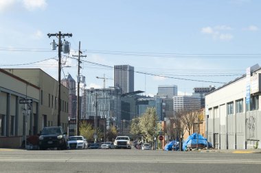 Portland, Oregon / ABD - 2019 dolaylarında kaldırımda evsiz çadırları bir caddenin yanında ve Portland Oregon şehrinin silueti uzaklarda görüldü.