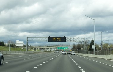 Portland, OR / USA - 29 Mart 2020: I205 otoyolundaki elektronik tabela, enfeksiyon kapma veya koronavirüs COVID-19 virüsü kapma riskini azaltarak insanları evlerinde kalmaları ve hayat kurtarmaları konusunda uyardı.