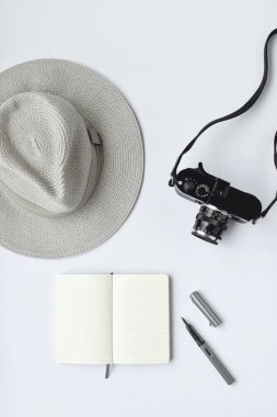 Defter, kalem, şapka ve beyaz arka plan üzerinde kamera