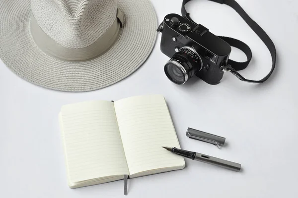 Notebook, pen, hat, and camera, on white background
