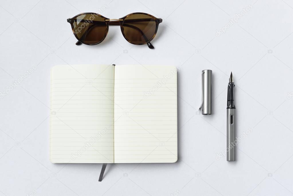 Sunglasses, notebook, and pen, on white background