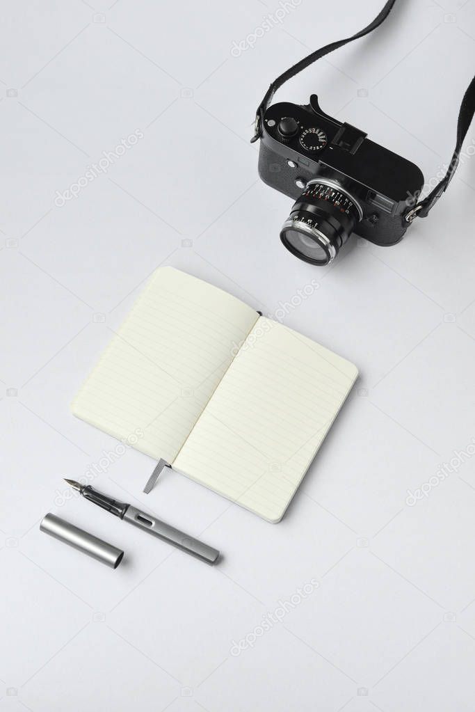 Notebook, pen, and camera, on white background